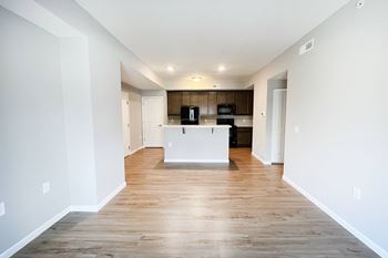 an empty living room and kitchen with white walls and wood flooring